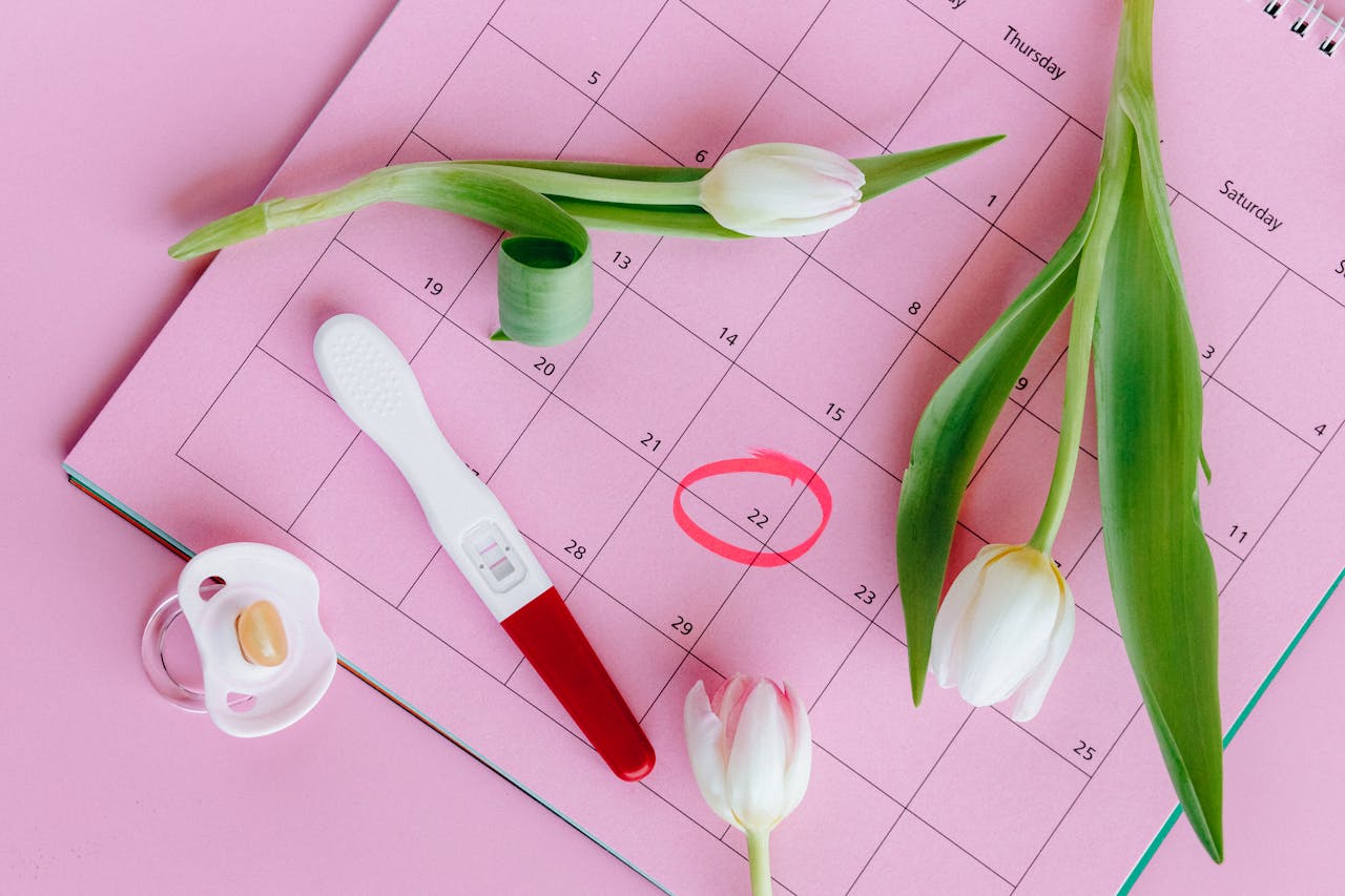 our-story Pregnancy test on pink calendar with tulips, symbolizing fertility and new beginnings.